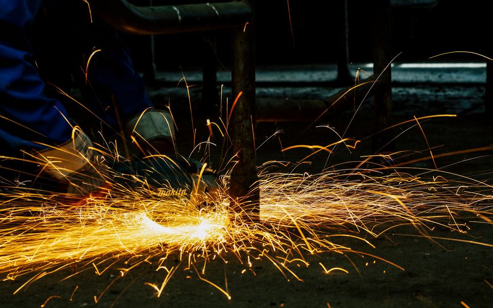Gloved hands working with metal in an industrial setting